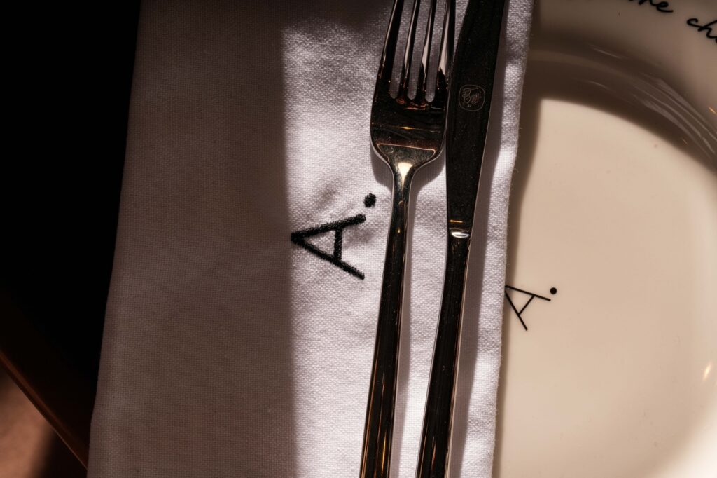 Close-up of cutlery on a white A Pasta Bar napkin beside a branded plate.