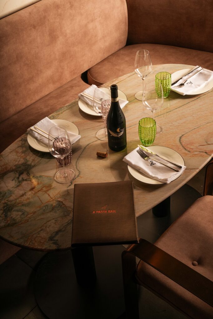 Oval stone table set for four beside a curved upholstered banquette.