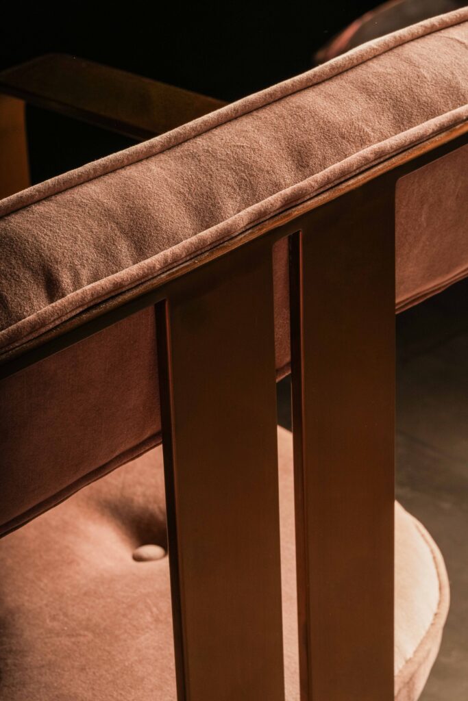 Rear view of a brown upholstered restaurant chair with a wooden frame.