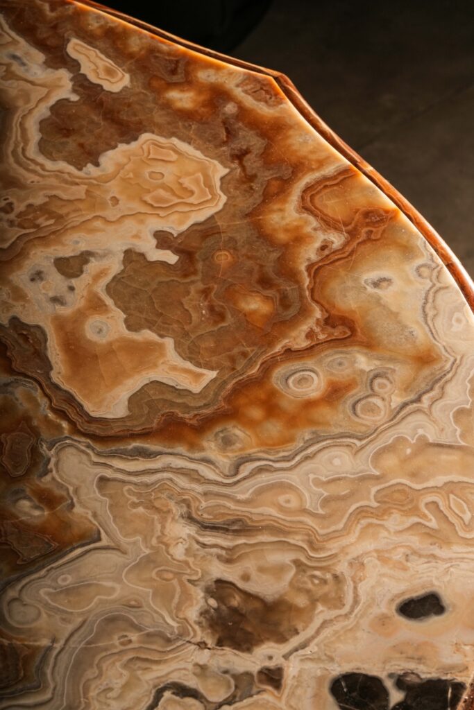 Close-up of a polished stone tabletop with swirling amber and cream patterns.