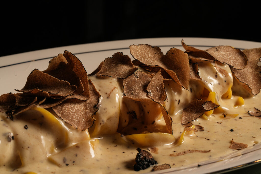Close-up of pasta in a creamy sauce topped with thin truffle shavings.