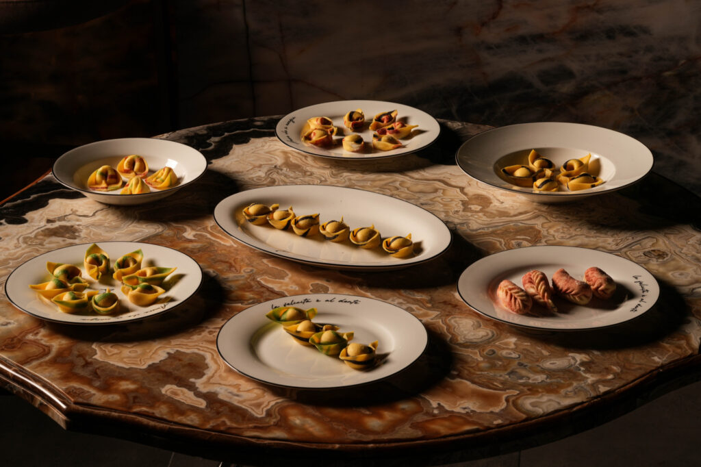 Assorted pasta dishes and cream-filled pastries arranged on a marble table.