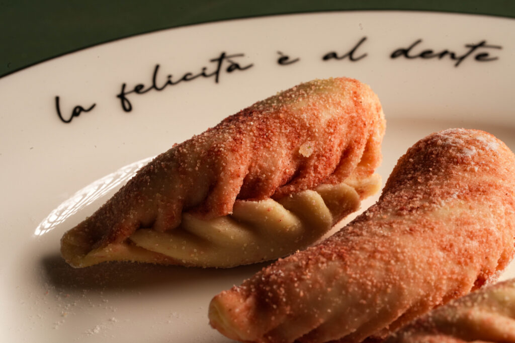 Two sugar-dusted pastries filled with cream on a white plate.