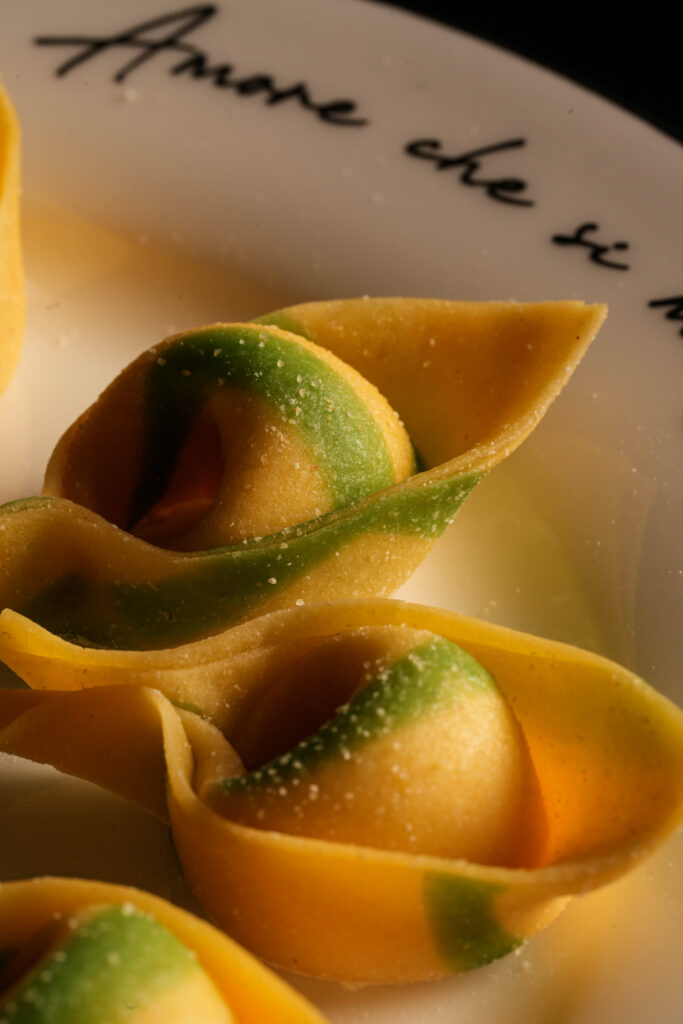 Folded pasta parcels topped with green sauce on a white plate.